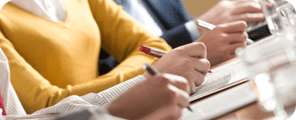 Image of hands taking notes during a conference.